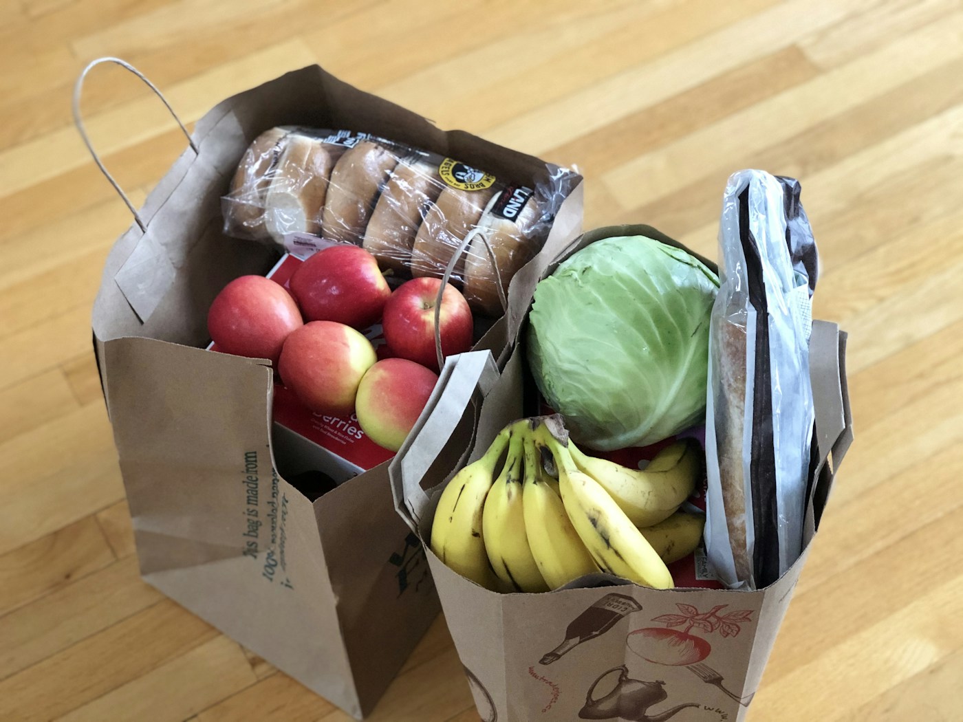 Paper grocery bags filled with fresh produce and bread